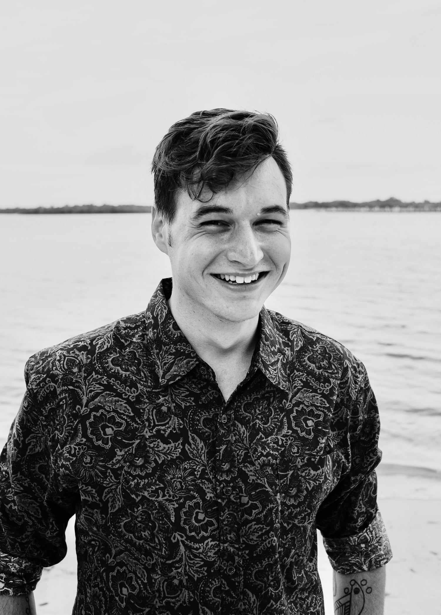 Black and white photo of Artist J Caleb Thompson standing by a body of water.